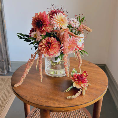 Pink and peach dahlia bouquet in a clear glass vase with a matching boutonniere