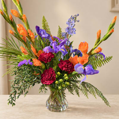 Colorful bouquet in a clear glass vase with orange, purple, and red flowers