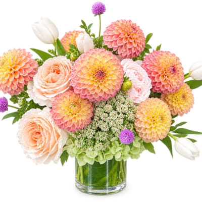 Peach and pink flowers in a glass vase with white tulips