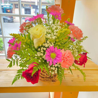 Mixed bouquet in a wicker basket with roses, carnations, and daisies