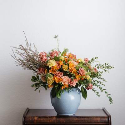 Mixed bouquet of pink and orange flowers in a blue vase