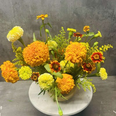 Orange and yellow marigold arrangement in a round vase