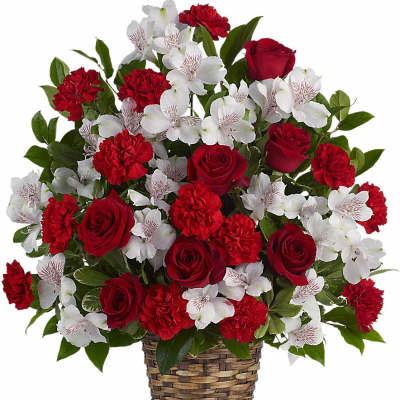 Red roses, red carnations, and white alstroemeria arranged in a woven basket