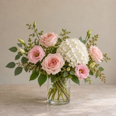 Pink roses and lisianthus with white hydrangea in a clear glass vase