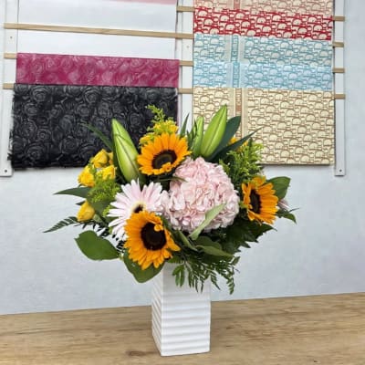 Sunflower and hydrangea arrangement in a white vase