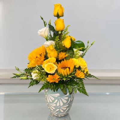Yellow and white floral arrangement in a patterned ceramic vase