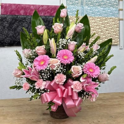 Pink floral arrangement in a basket with a large ribbon