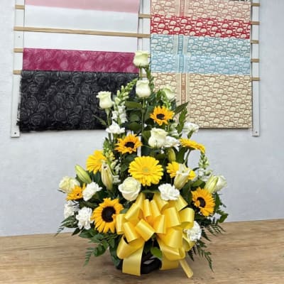 Yellow and white floral arrangement with a large yellow bow