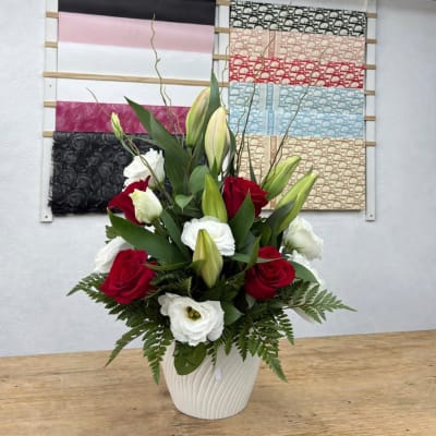 Red roses and white lilies arranged in a white vase