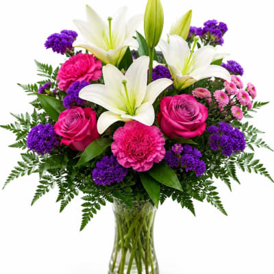 Bouquet of white lilies, pink roses, and purple flowers in a glass vase
