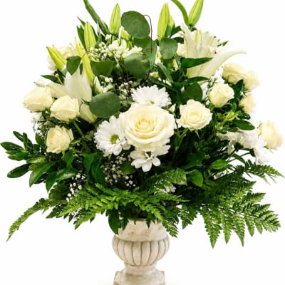 White roses and lilies arranged in a cream urn vase