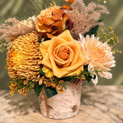 Orange rose and chrysanthemum arrangement in a birch vase