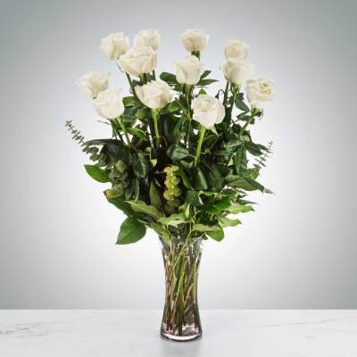 Tall arrangement of long-stem white roses in a clear glass vase