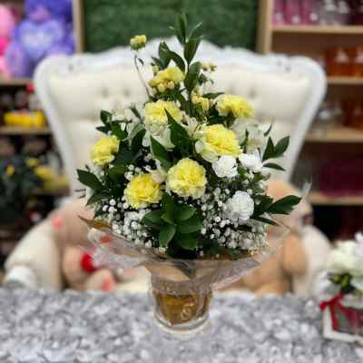Yellow and white carnation bouquet with baby's breath in a clear vase