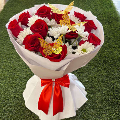 Bouquet of red roses and white daisies wrapped in white paper