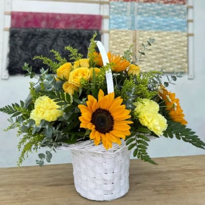 Yellow flowers in a white basket with a sunflower centerpiece