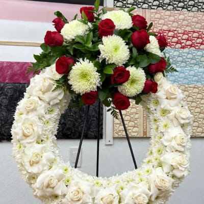 Large floral wreath with red and white roses on a black stand