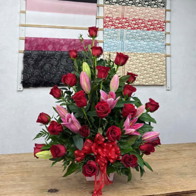 Red roses and pink lilies in a white vase with a red bow