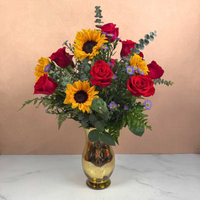 Red roses and sunflowers arranged in a gold vase