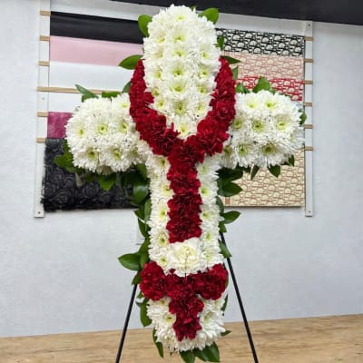 White and red floral cross on a black stand
