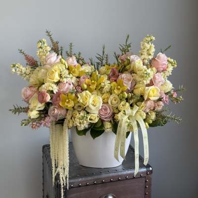 Large pastel flower arrangement in a white vase with pink and yellow blooms