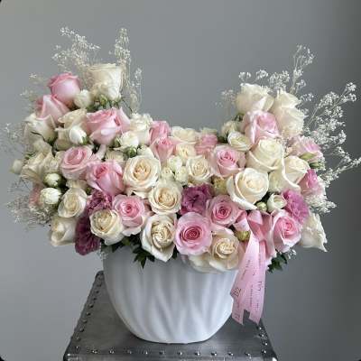 Pink and white rose arrangement in a white vase