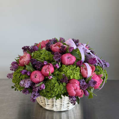 Pink peonies and purple lilacs in a white basket
