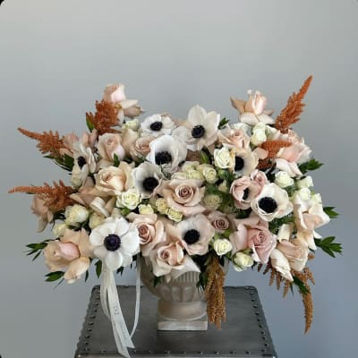 Blush and white floral arrangement in a pedestal vase