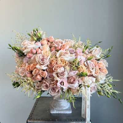 Large bouquet of blush and peach roses in a square vase