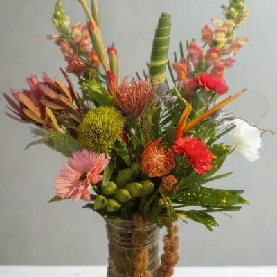 Tropical bouquet in a glass vase with pink and orange blooms