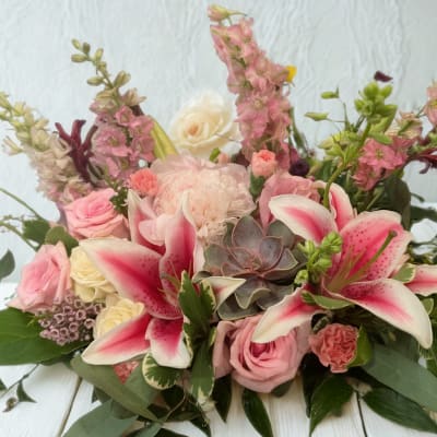 Pink lilies and roses arranged with a succulent in a low bouquet