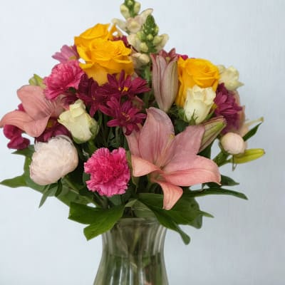 Mixed bouquet of pink, yellow, and white flowers in a glass vase
