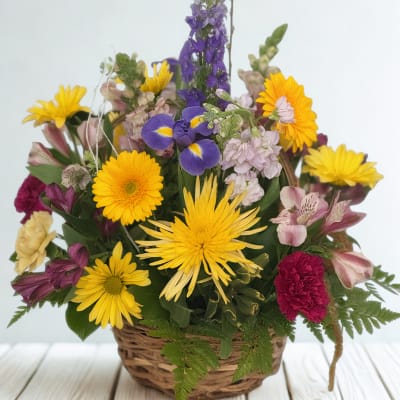 Mixed flower basket with yellow daisies, purple iris, and pink blooms