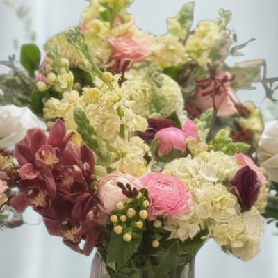 Mixed pink, cream, and burgundy flowers in a glass vase