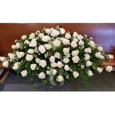 Large white rose arrangement on a wooden casket