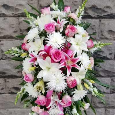Standing floral spray with pink roses, white lilies, and white daisy-like blooms