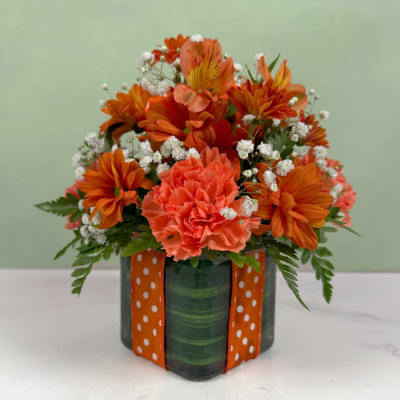 Orange bouquet in a green vase with a polka-dot ribbon