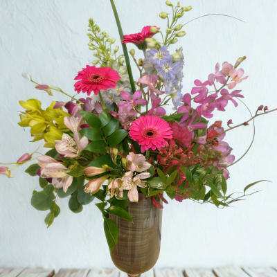 Mixed bouquet of pink gerberas and pastel flowers in a tall vase