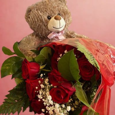Teddy bear holding a bouquet of red roses