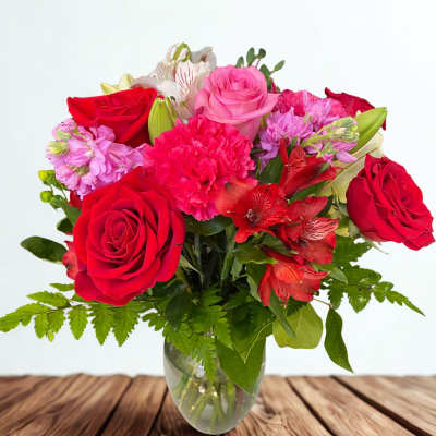 Bouquet of red and pink roses with carnations in a glass vase