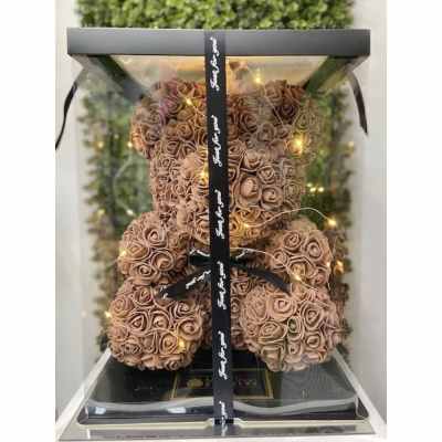 Teddy bear made of peach artificial roses in a clear gift box with ribbon and string lights