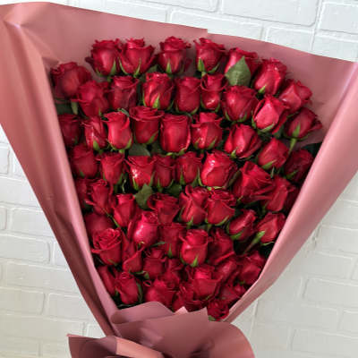 Large bouquet of red roses wrapped in pink paper with a striped ribbon