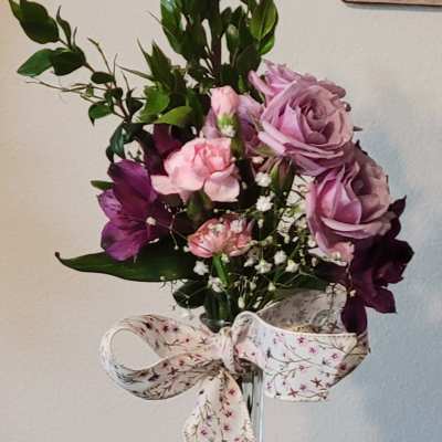 Pink and purple bouquet in a clear glass vase with a patterned ribbon