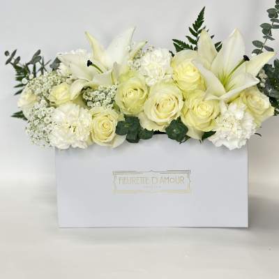 White roses and lilies arranged in a white gift box
