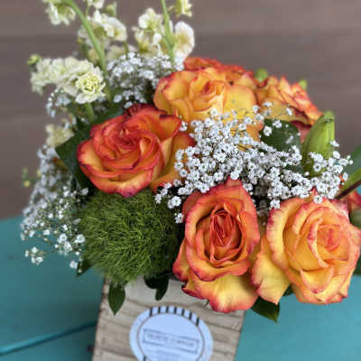 Orange roses in a wooden box with white filler flowers