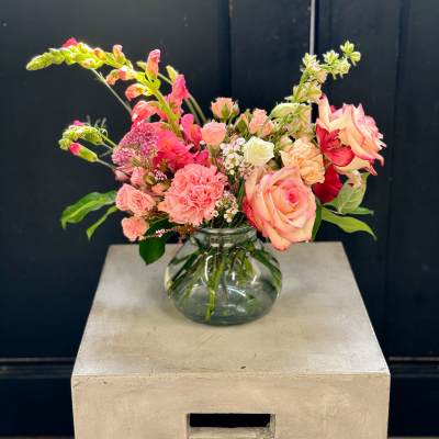 Pink and peach flowers arranged in a clear glass vase