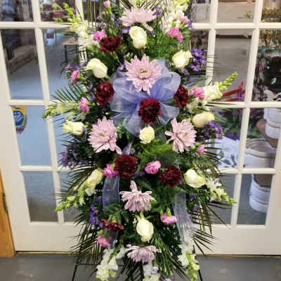 Standing floral spray with pink, white, and purple flowers on an easel