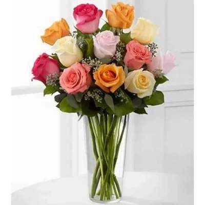 Tall clear vase of mixed pink, peach, yellow, and cream roses