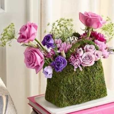 Pink and purple roses arranged in a moss-covered rectangular container