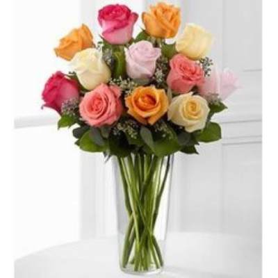 Tall clear vase of mixed pink, peach, yellow, and cream roses